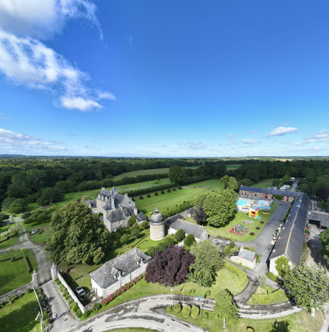 Luftfoto af Camping Domaine du Logis i Bretagne, Frankrig, omgivet af grønne marker og blå himmel.