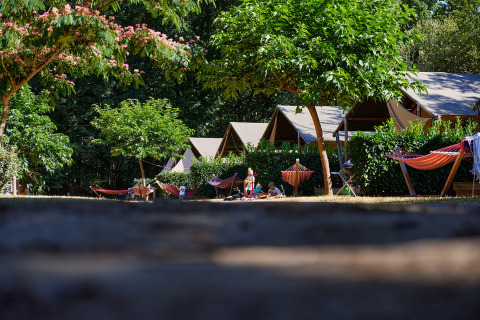 Tiendas, hamacas y árboles en el Camping Domaine du Logis en Bretaña, Francia, durante el verano.