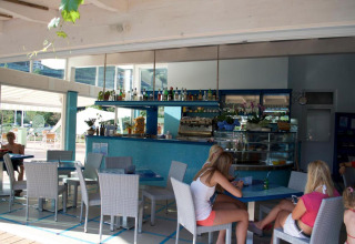 Binnenruimte van café op Camping Delle Rose in Ligurië, Italië, met gasten aan tafels in relaxte sfeer.