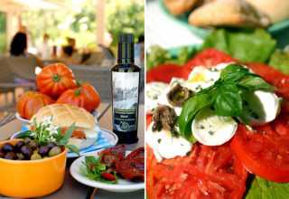 Pomodori, mozzarella, olive, erbe fresche e pane serviti all’aperto al Camping Delle Rose in Liguria, Italia.