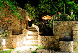 Scala e muri in pietra illuminati di notte con fiori al Camping Delle Rose, Liguria, Italia.