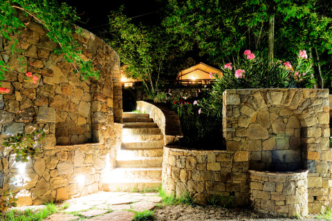 Escalier et murs de pierres illuminés la nuit entourés de fleurs au Camping Delle Rose, Ligurie, Italie.