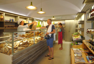 A grocery store at Camping Delle Rose in Liguria, Italy, with guests buying fresh bread and groceries.