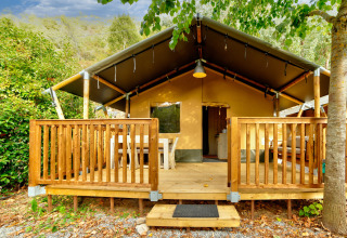 Tente safari avec terrasse en bois au Camping Delle Rose, Ligurie, Italie, entourée de verdure et d’arbres.
