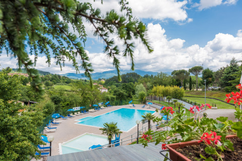 Piscina con lettini prendisole e vista panoramica sulla Toscana al Camping Il Poggetto, Italia.