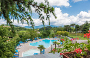 Piscina con lettini prendisole e vista panoramica sulla Toscana al Camping Il Poggetto, Italia.