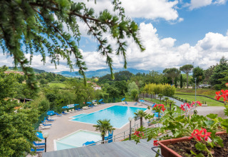 Swimming pool with sun loungers and scenic Tuscan views at Camping Il Poggetto holiday park, Italy.
