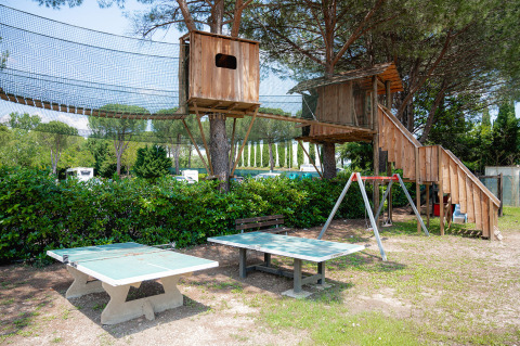 Legeområde med træhytte, bordtennisbord og gyngestativ på Camping Il Poggetto, Toscana, Italien.