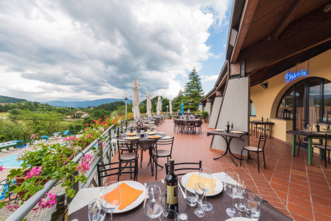 Terrazza ristorante all'aperto al Camping Il Poggetto con vista sulla campagna e le colline toscane.