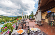 Udendørs restaurantterrasse på Camping Il Poggetto med udsigt over det toscanske landskab og bjerge.