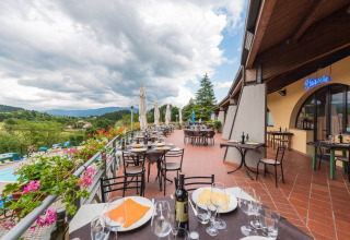 Buitenterras van het restaurant bij Camping Il Poggetto met uitzicht op het Toscaanse landschap en de heuvels.