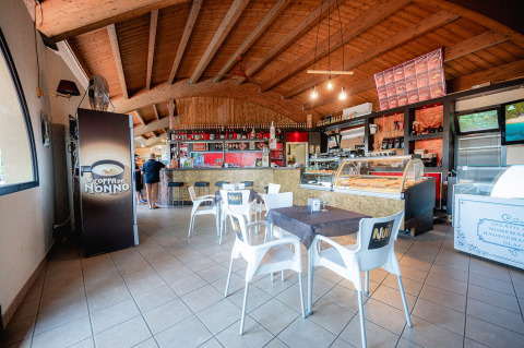 Cafetería interior con techo de madera y mostrador de helados en Camping Il Poggetto, Toscana, Italia.