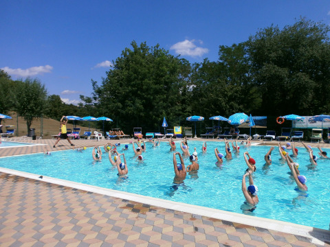 Groep doet aquarobics in het zwembad bij Camping Il Poggetto op een zonnige dag in Toscane, Italië.