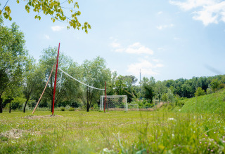 Buitensportveld met volleybalnet en voetbaldoelen op Camping Il Poggetto in Toscane, Italië.