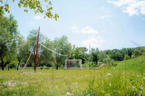 Area sportiva all'aperto con rete da pallavolo e porte da calcio al Camping Il Poggetto in Toscana.