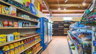 Pequeña tienda en Camping Il Poggetto, Toscana, con bebidas, alimentos y juguetes de playa.