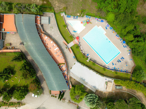 Vista aerea di Camping Il Poggetto in Toscana, Italia, con piscina, lettini e aree verdi.
