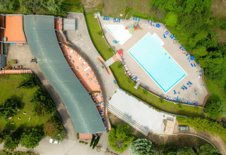 Vista aérea de Camping Il Poggetto en Toscana, Italia, mostrando piscina, tumbonas y zonas verdes.