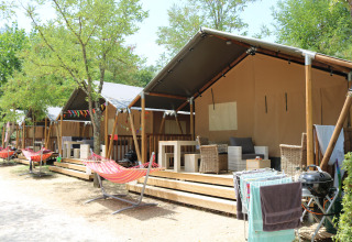 Glampingtenten met veranda en hangmat bij Camping Il Poggetto, een vakantiepark in Toscane, Italië.