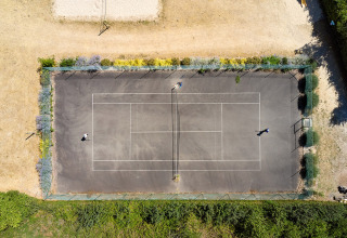 Aerial view of a tennis court at Camping La Bretonnière, Pays de la Loire, France, with two people playing.