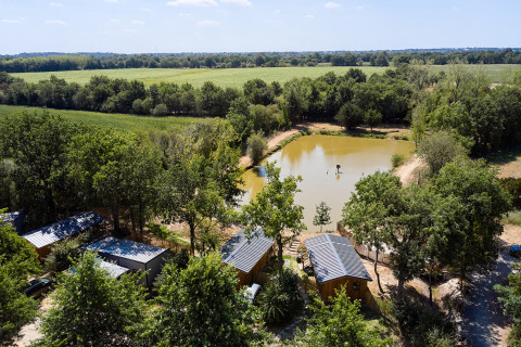 Vista aérea de Camping La Bretonnière, un parque vacacional en Pays de la Loire, Francia, con cabañas y lago.