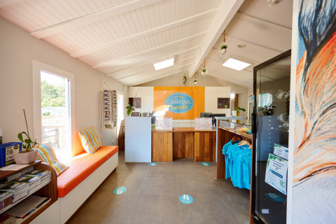 Recepción de Camping La Bretonnière, colores vivos, folletos y ambiente acogedor en Pays de la Loire, Francia.