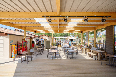 Overdekt terras met tafels bij Camping La Bretonnière, vakantiepark in Pays de la Loire, Frankrijk.