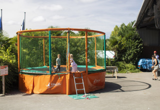 Bambini che giocano su un grande trampolino con rete di sicurezza al Camping La Bretonnière, Pays de la Loire, Francia