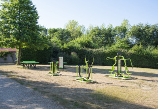 Outdoor gym equipment and picnic table on grassy area at Camping La Bretonnière, Pays de la Loire, France.
