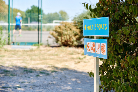 Multisports sign at Camping La Bretonnière, Pays de la Loire, France, beside a man playing tennis.