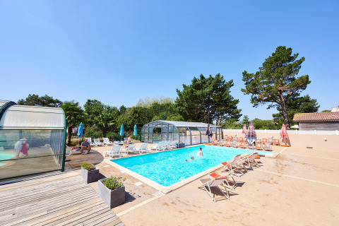 Outdoor swimming pool with sun loungers and umbrellas at Camping La Bretonnière holiday park, Pays de la Loire, France.