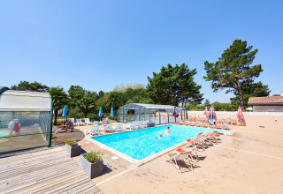 Outdoor swimming pool with sun loungers and umbrellas at Camping La Bretonnière holiday park, Pays de la Loire, France.