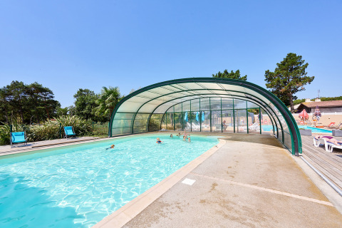 Outdoor swimming pool with partial cover at Camping La Bretonnière in Pays de la Loire, France.