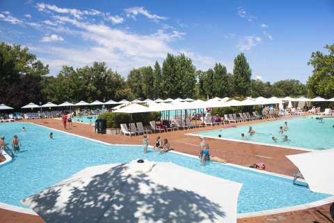 Camping La Chiocciola in Toscana, Italia, con piscine, ombrelloni bianchi e ospiti che si rilassano al sole.
