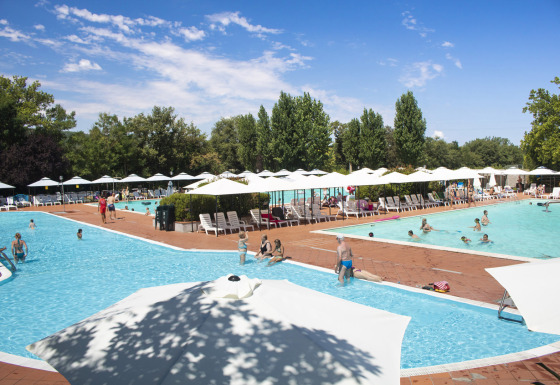 Feriepark Camping La Chiocciola i Toscana, Italien, med swimmingpools, parasoller og solbadende gæster.
