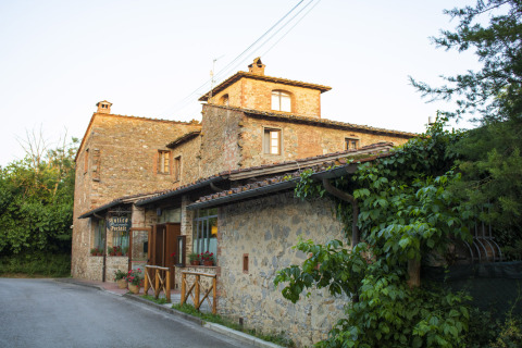 Edificio in pietra immerso nel verde al Camping La Chiocciola, parco vacanze in Toscana, Italia, al tramonto.