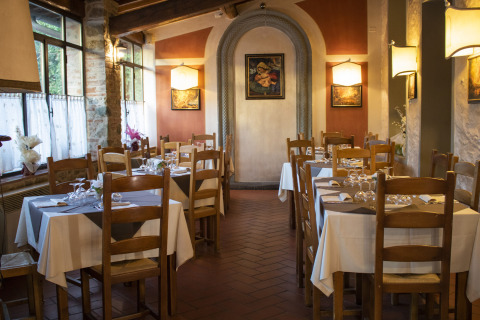 Acogedor restaurante con mesas puestas y sillas de madera en Camping La Chiocciola en la Toscana, Italia.
