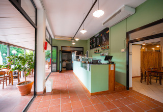 Rezeption und Barbereich im Camping La Chiocciola in der Toskana, Italien, mit Tischen und Pflanzen.