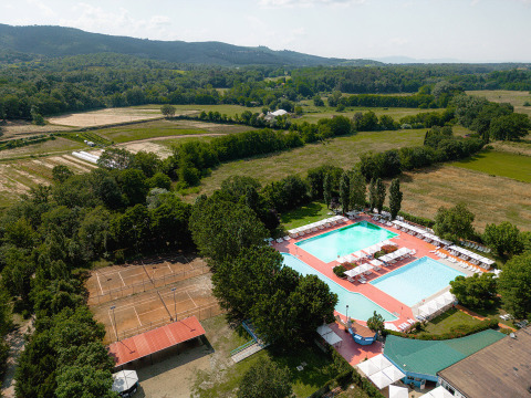 Vista aérea de Camping La Chiocciola en la Toscana, Italia, con piscinas, canchas de tenis y campos verdes.