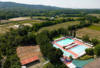 Vista aerea di Camping La Chiocciola in Toscana, Italia, con piscine, campi da tennis e campi verdi circostanti.