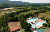 Aerial view of Camping La Chiocciola in Tuscany, Italy, showing pools, tennis courts, and scenic fields.