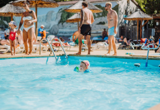 Kinderen en volwassenen genieten van een zonnige dag aan het zwembad bij Camping La Clémentine in Occitanië, Frankrijk.