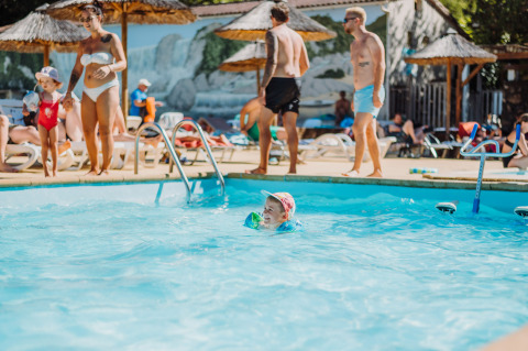 Niños y adultos disfrutan de un día soleado en la piscina de Camping La Clémentine en Occitanie, Francia.