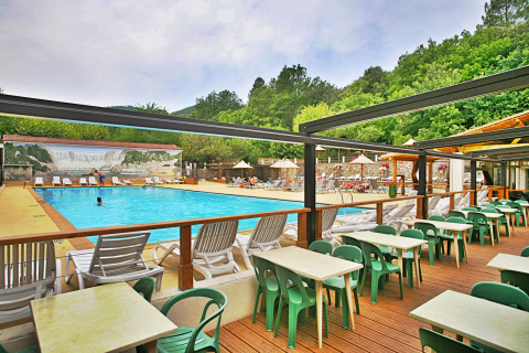 Piscina all'aperto con lettini e area pranzo esterna al Camping La Clémentine in Occitania, Francia.