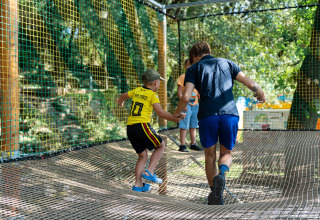 Bambini che giocano su una rete sospesa in un parco avventura al Camping La Clémentine, Occitania, Francia.
