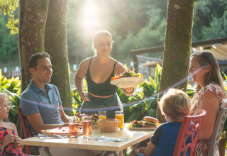 Een gezin dineert buiten met bediening bij Camping La Clémentine vakantiepark in Occitanië, Frankrijk.