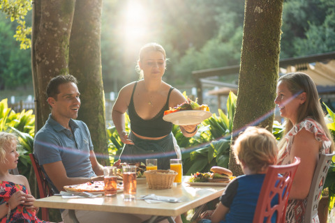Una familia disfruta de una comida al aire libre servida en Camping La Clémentine, Occitanie, Francia.