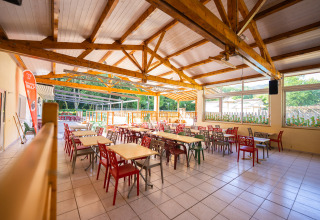 Eetzaal met kleurrijke stoelen en uitzicht op de tuin, Camping La Clémentine, Occitanië, Frankrijk.