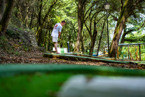 Un hombre juega al minigolf en un parque de vacaciones boscoso en Camping La Clémentine, Occitania, Francia.