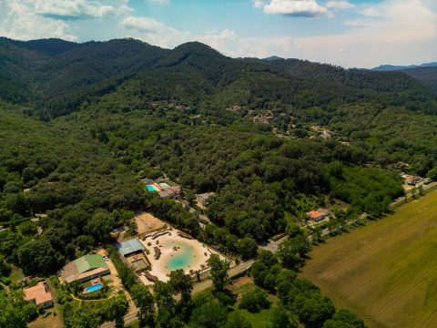 Vista aerea del villaggio vacanze Camping La Clémentine immerso tra le colline boscose dell'Occitania, Francia.